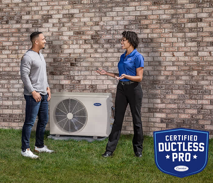 carrier-certified-ductless-pro-talking-to-homeowner-next-to-a-heat-pump